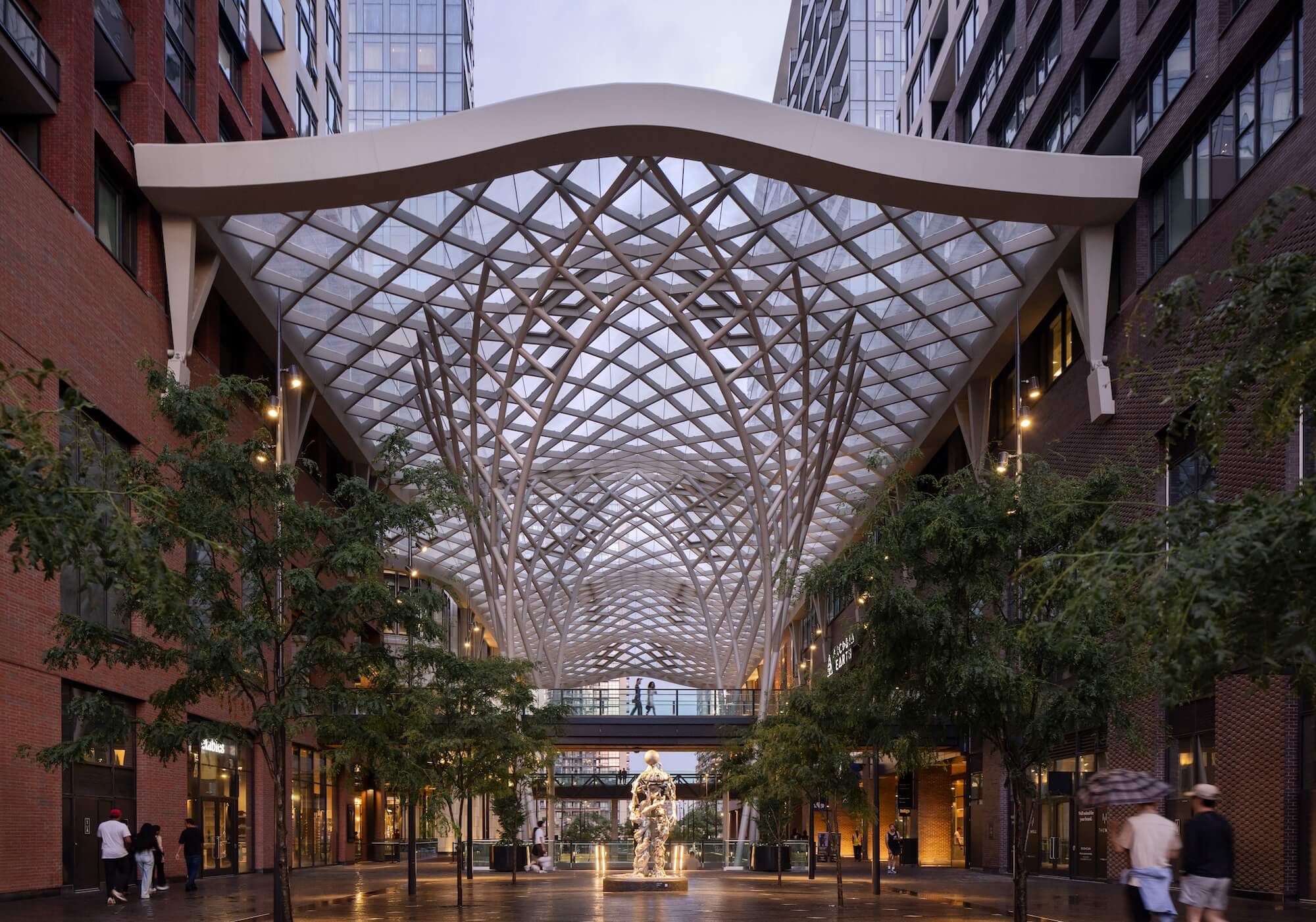 Modern architectural interior with a geometric ceiling design and people walking around.