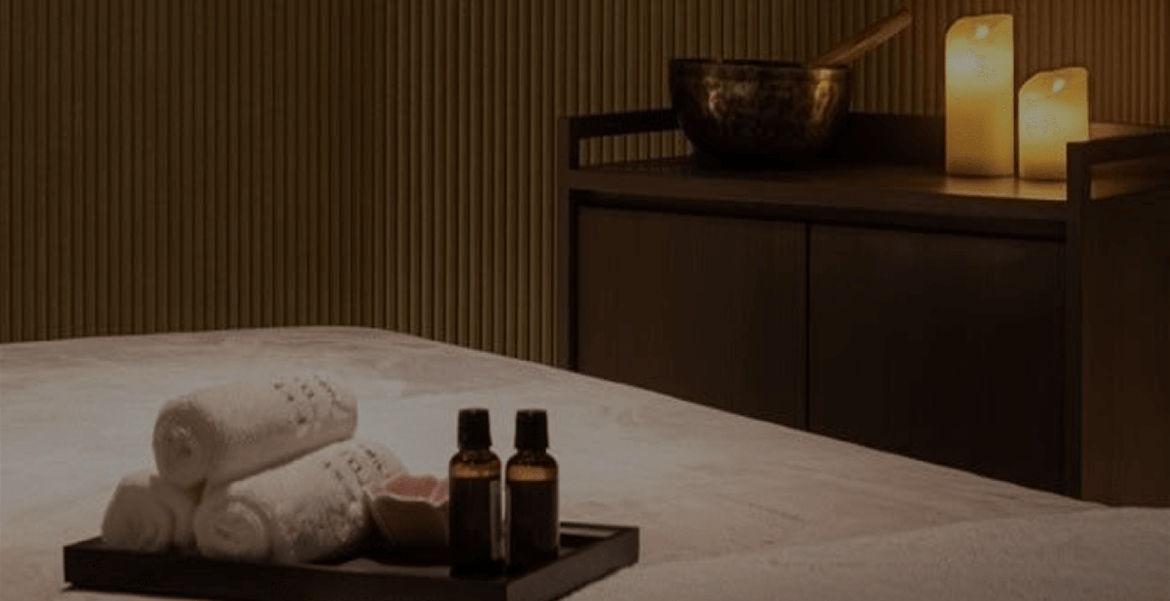 Spa setting with towels, bottles, and candles on a table.
